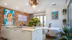 Een moderne keuken met een centraal eiland, een eethoek met een ronde tafel en kunst aan de muur.