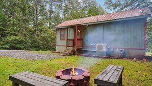 Une cabane rustique avec un foyer et deux bancs en bois devant.