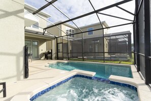 An outdoor swimming pool with a hot tub, surrounded by a covered patio area with a view of neighboring buildings. - Super Luxury Modern Home Prime Location (Kissimmee)