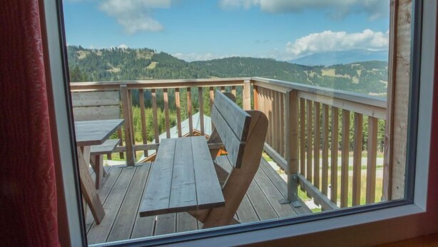 A balcony with wooden railings and a wooden table, overlooking a mountainous landscape. - Alpenchalet 341 by Interhome (Klippitztörl)