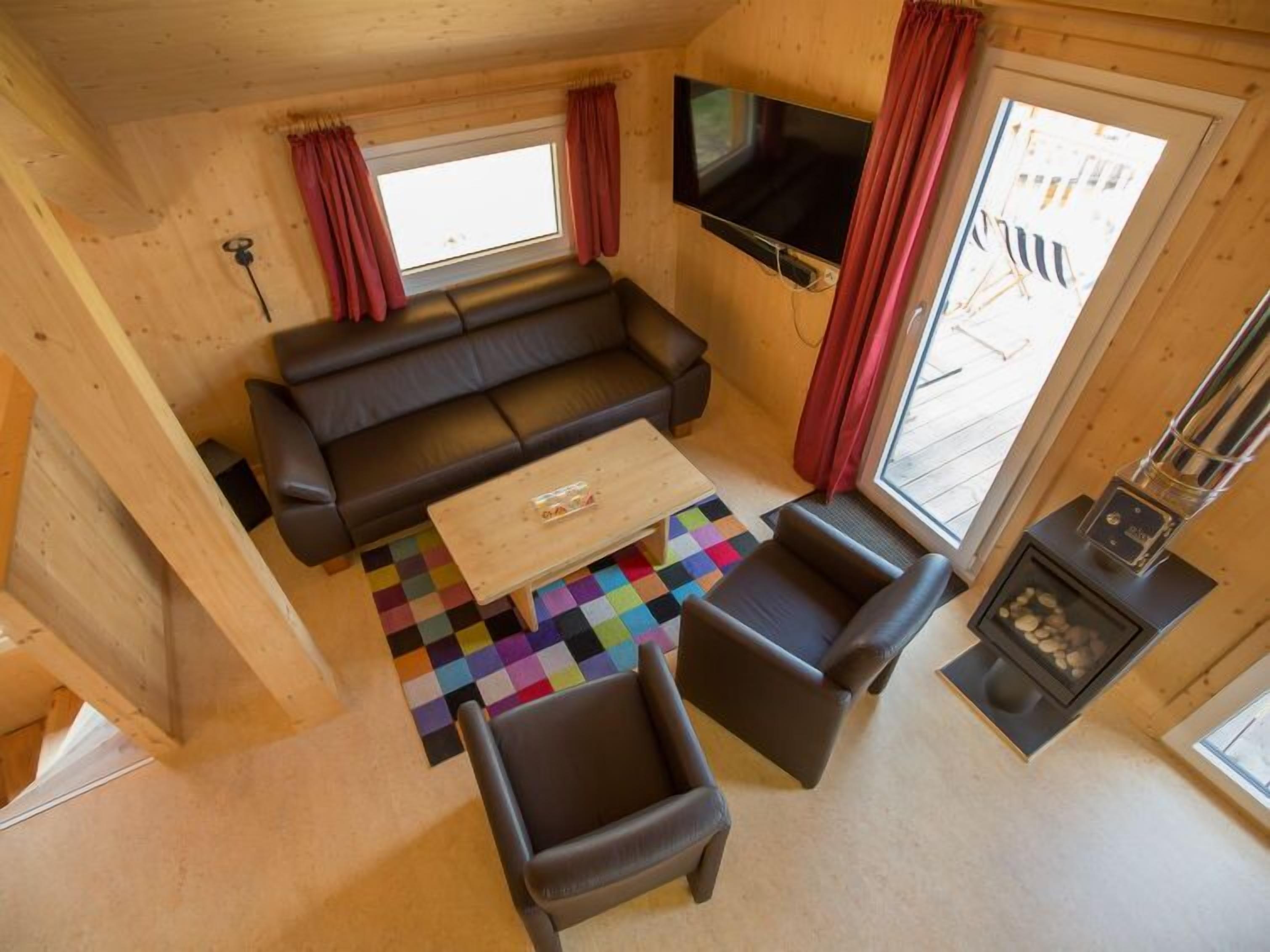 Ein gemütliches Wohnzimmer mit einer Couch, zwei Sesseln, einem Couchtisch und einem Flachbildfernseher.