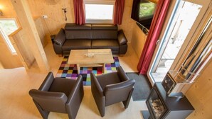 A cozy cabin interior with a sofa, two armchairs, a coffee table, a TV, and a fireplace. - Alpenchalet 341 by Interhome (Klippitztörl)