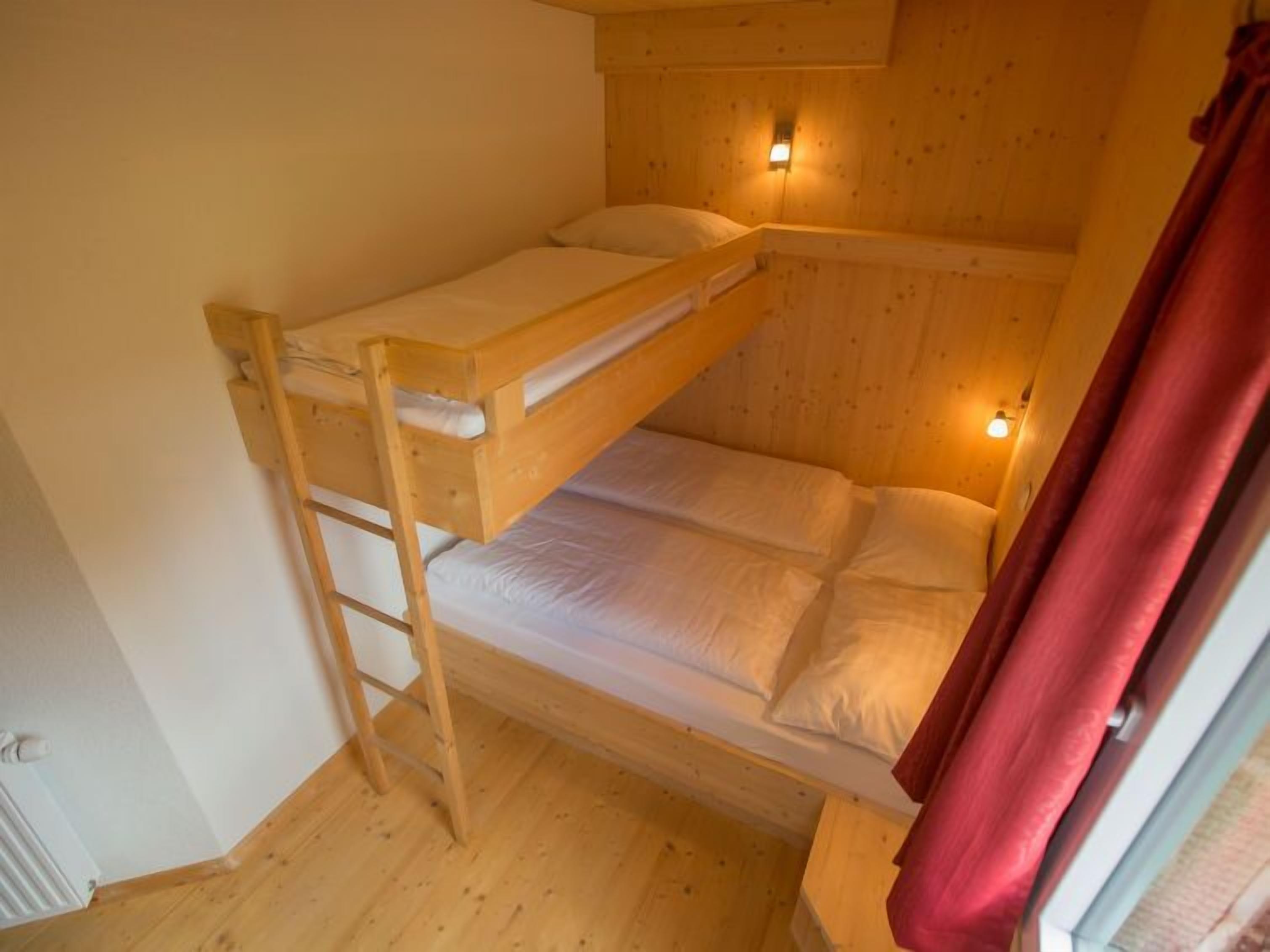 A bunk bed room with wooden walls and a ladder.