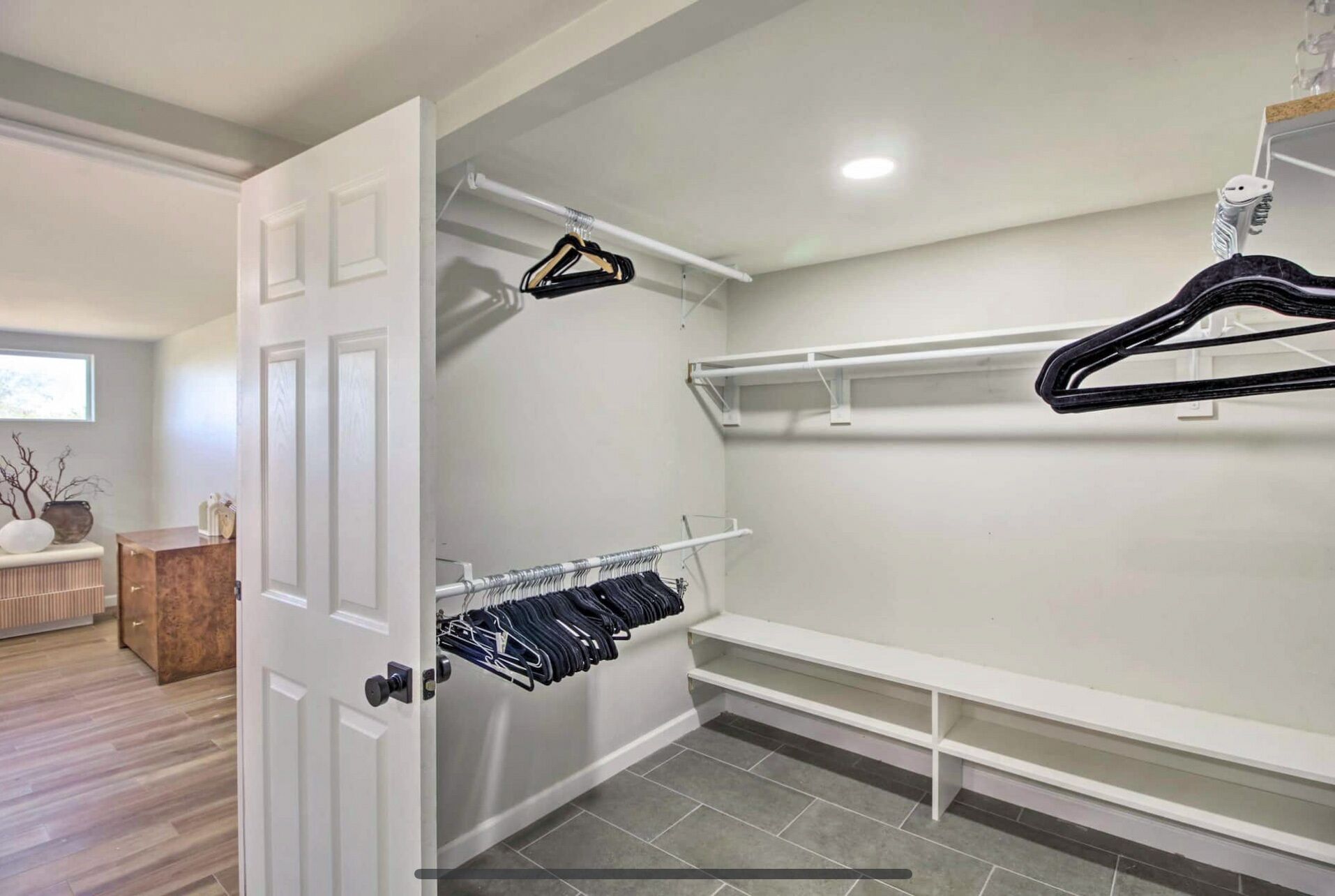 A walk-in closet with a hanging rod, shelves, and a bench.