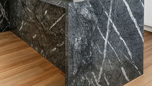 Una cocina moderna con una isla grande de granito, electrodomésticos de acero inoxidable y armarios blancos.