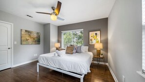 A bedroom with a bed, a ceiling fan, a window, and two wall-mounted lamps. - Stylish 2BR near City Center | OTR, UC, Zoo (Cincinnati)
