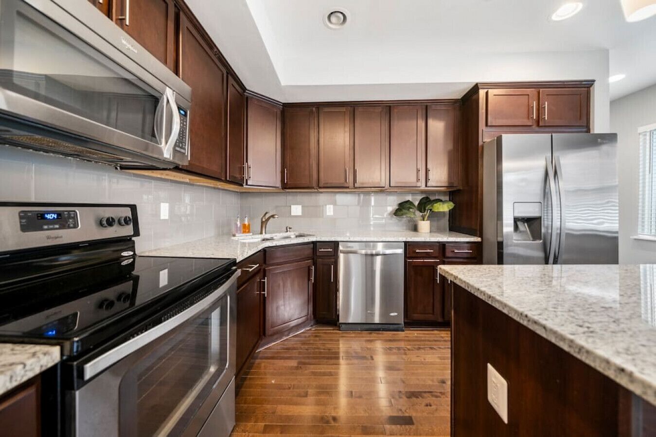 A modern kitchen with dark wood cabinets, stainless steel appliances, and a granite countertop.