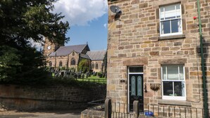 Un bâtiment en pierre avec une porte noire et une fenêtre.