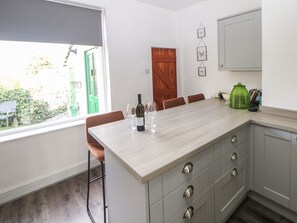 Una cocina con una isla de madera, taburetes de bar y vistas al exterior.
