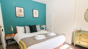 Une chambre à coucher avec un lit, une table de chevet, une commode et une porte.