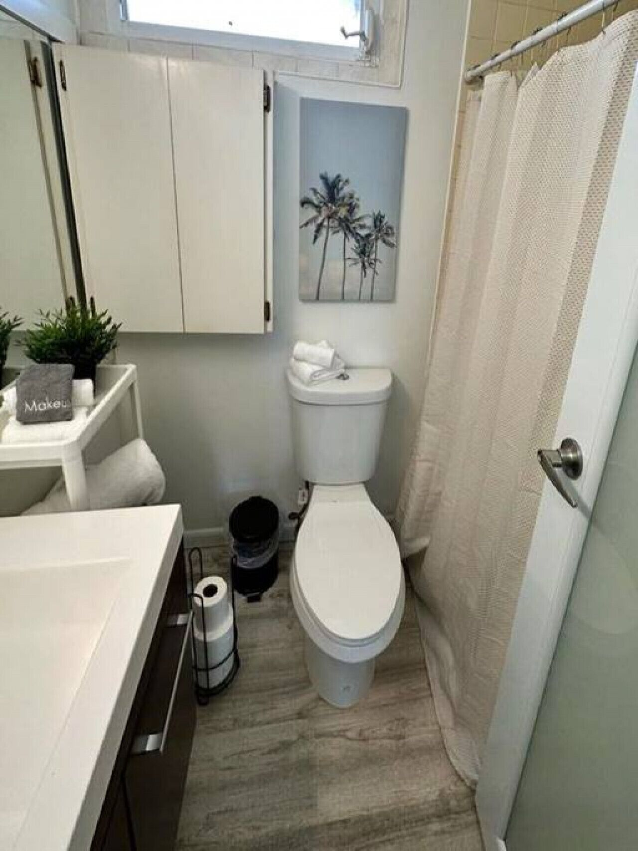 Un baño con inodoro, lavabo, espejo y cortina de ducha.