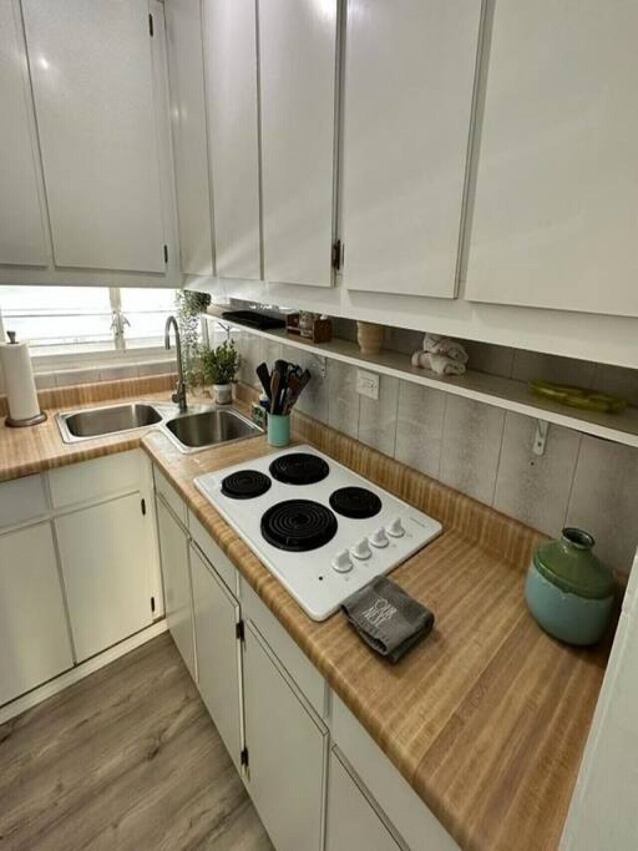 Una cocina moderna con armarios blancos, encimera de madera, estufa y pileta.