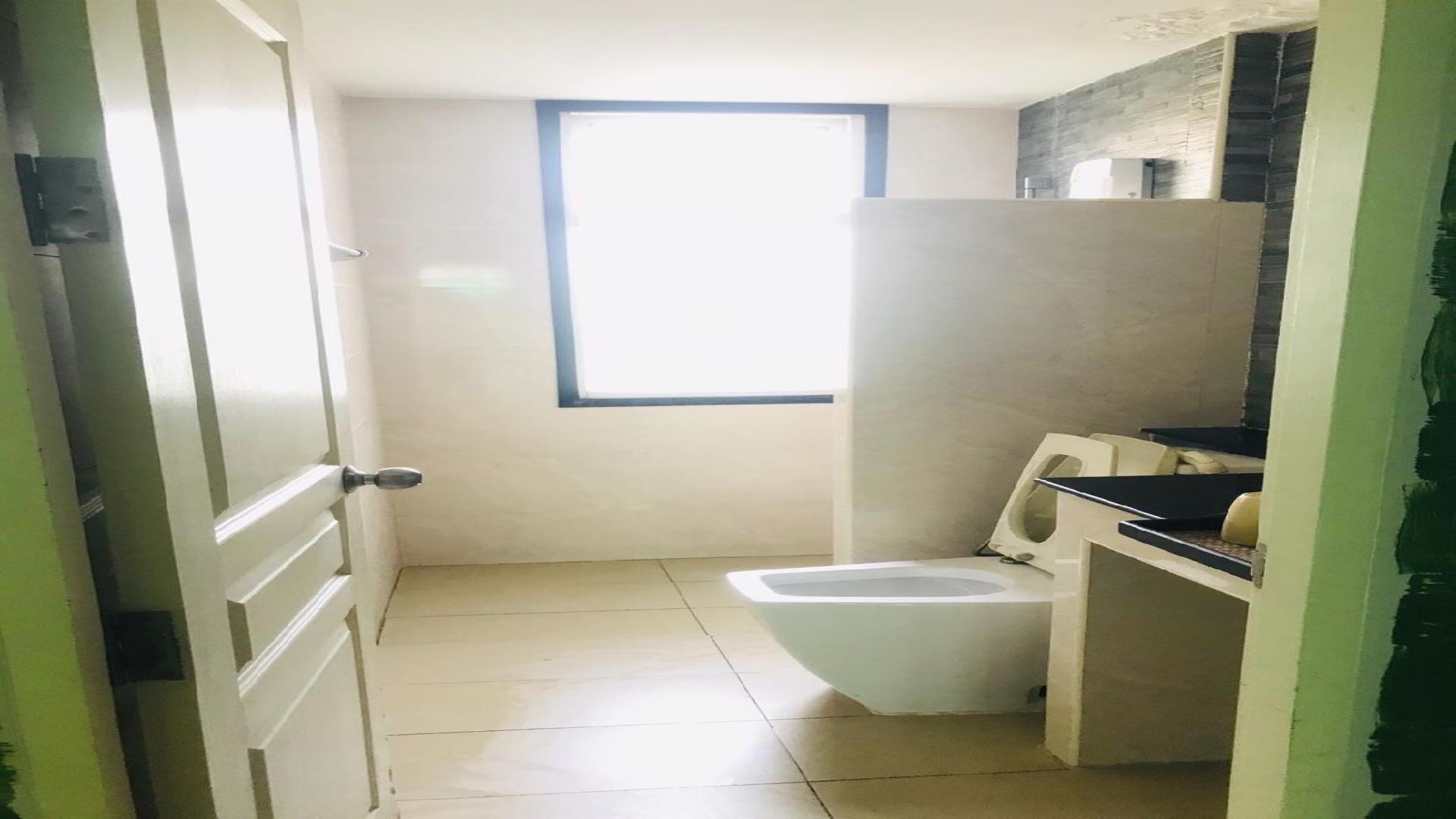 A small, basic bathroom with a toilet, a sink, and a window.