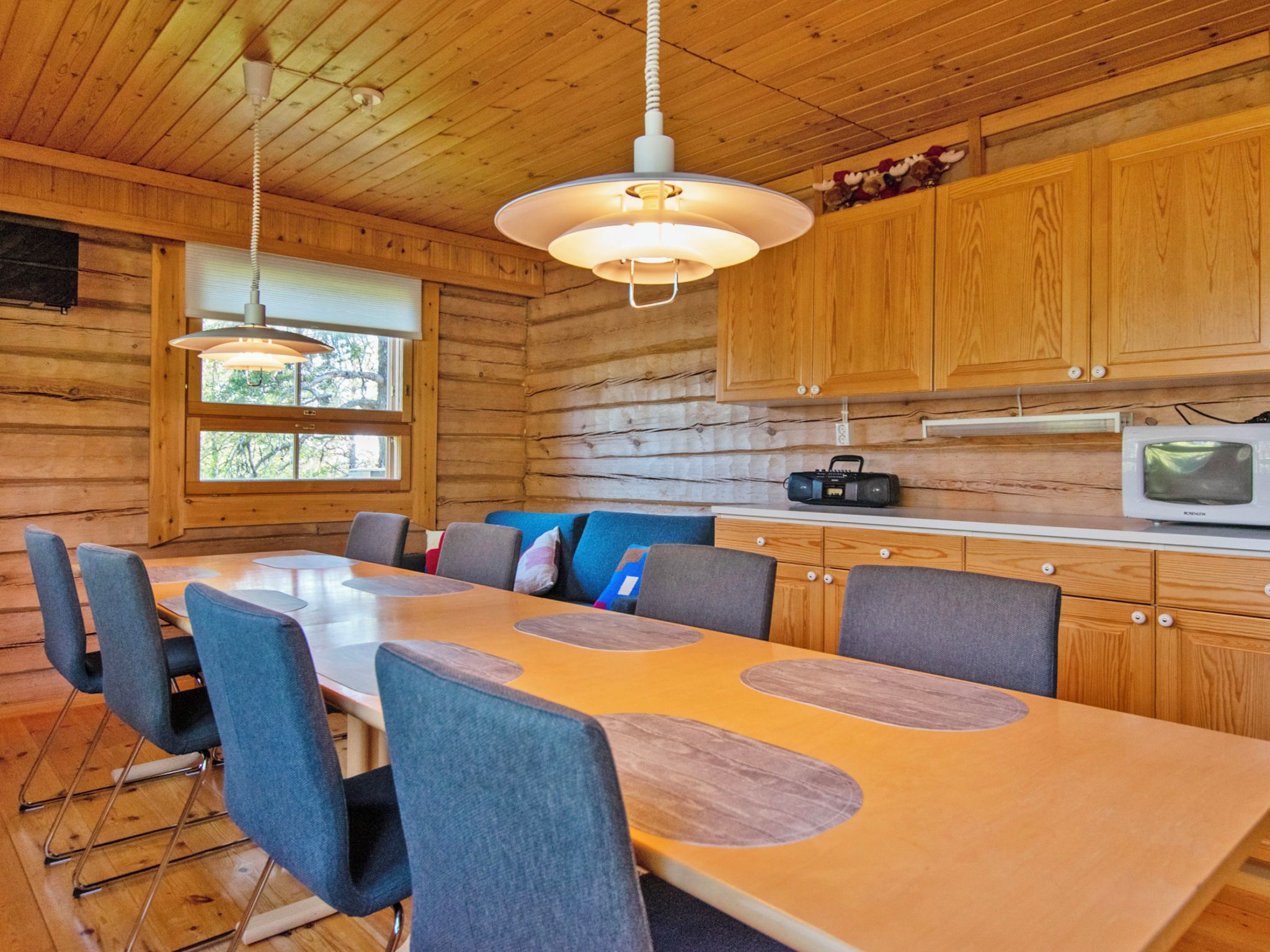Een houten hut interieur met een eettafel, stoelen, een radio en een televisie.