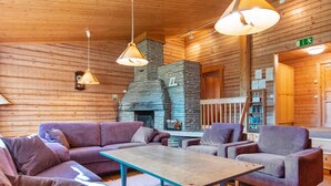A wooden interior with a fireplace, sofas, and a coffee table.