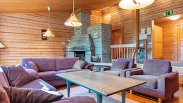 A cozy log cabin interior with a fireplace, wooden walls, and purple furniture.