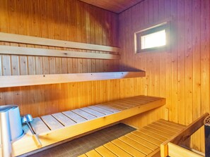 Un sauna avec des bancs en bois et une petite fenêtre.