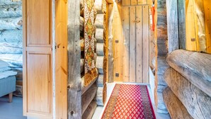A log cabin interior with a wooden door, a patterned rug, and a bench.