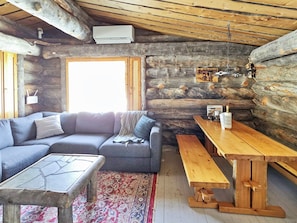 Ein Holzblockhaus-Interieur mit einer Couch, einem Holztisch und einer hängenden Leuchte.