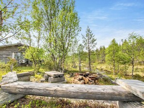 Eine rustikale Holzhütte mit einer Holzterrasse und einem Holzstapel.