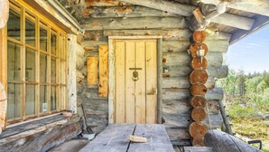 A log cabin with a wooden door, a window, and a bench outside.