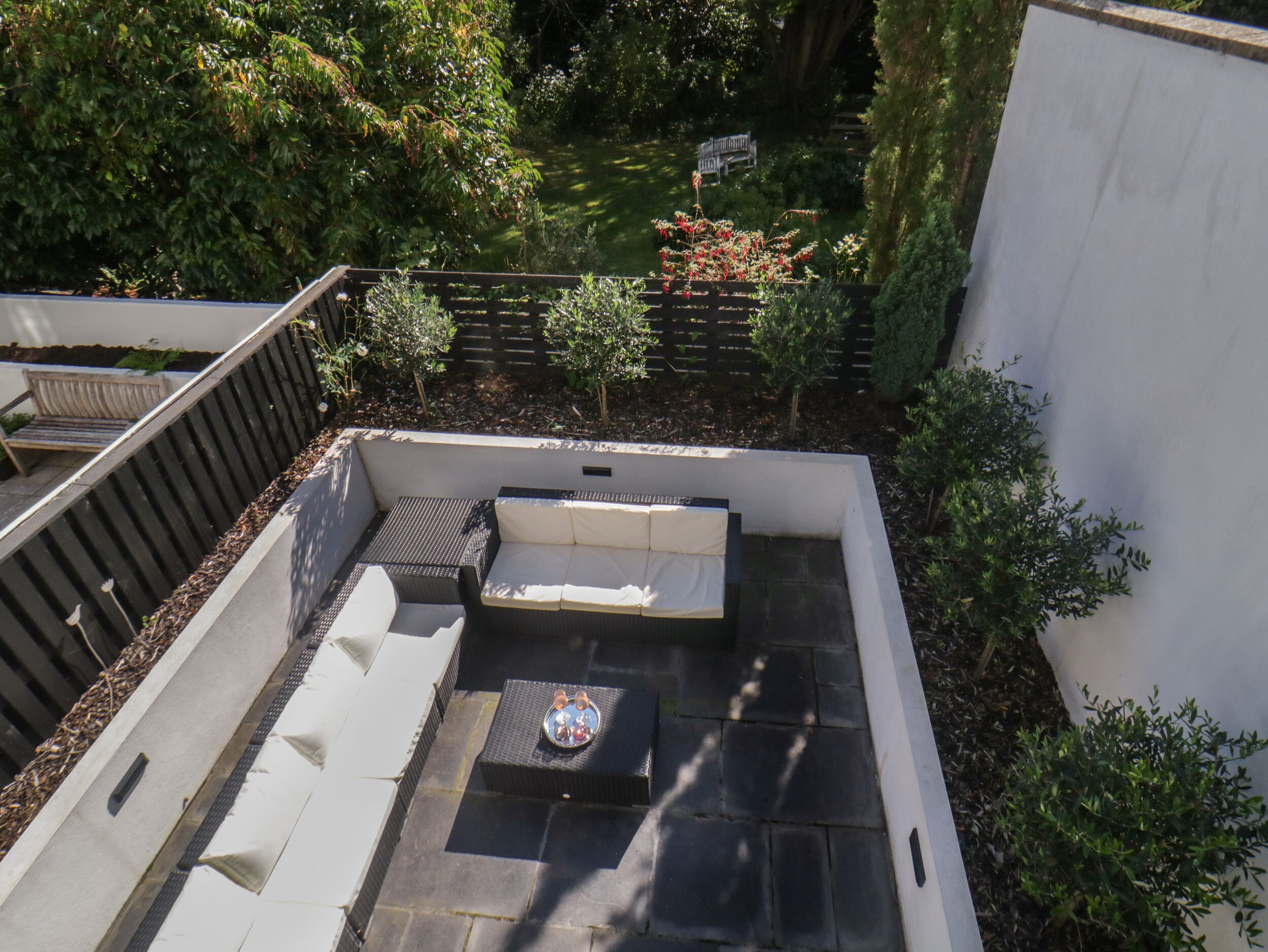 Une terrasse sur le toit avec un canapé, une petite table et un banc.