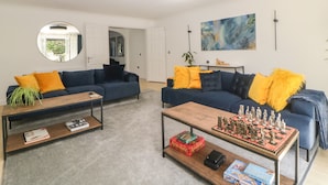 A modern living room with two sofas, a coffee table, and a chess table.