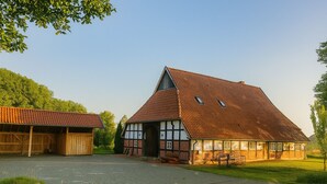 A traditional barn with a sloped roof and a wooden structure with a red-tiled roof.
