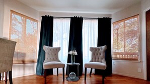 A room with two upholstered chairs, a small table with a vase, and a patterned rug.