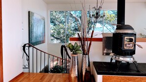 A wooden staircase leading to a landing with a view of trees outside.
