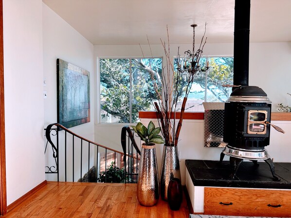 A wooden staircase leading to a landing with a view of trees outside.