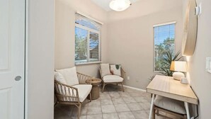 Une petite pièce bien éclairée, avec deux fauteuils en osier, une petite table et un luminaire au plafond.
