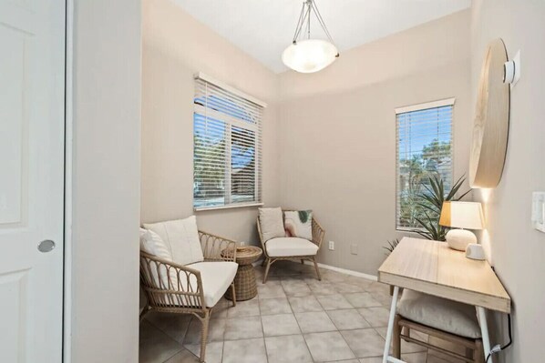 A small, well-lit room with two wicker chairs, a small table, and a ceiling light.
