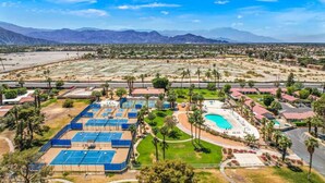 Vue aérienne d’un complexe hôtelier doté de plusieurs courts de tennis, d’une piscine et, en arrière-plan, d’un paysage désertique.