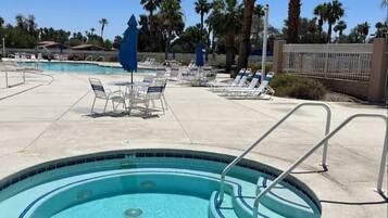A pool area with lounge chairs and umbrellas, surrounded by palm trees.