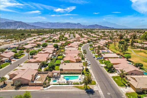 An aerial view of a residential area with houses, roads, and a swimming pool.