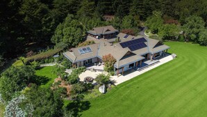 A large, multi-story house with solar panels, surrounded by lush greenery and a well-maintained lawn. - Kumiko's Guest House (Waipara)