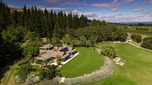A large house surrounded by a well-maintained lawn and dense forest. - Kumiko's Guest House (Waipara)