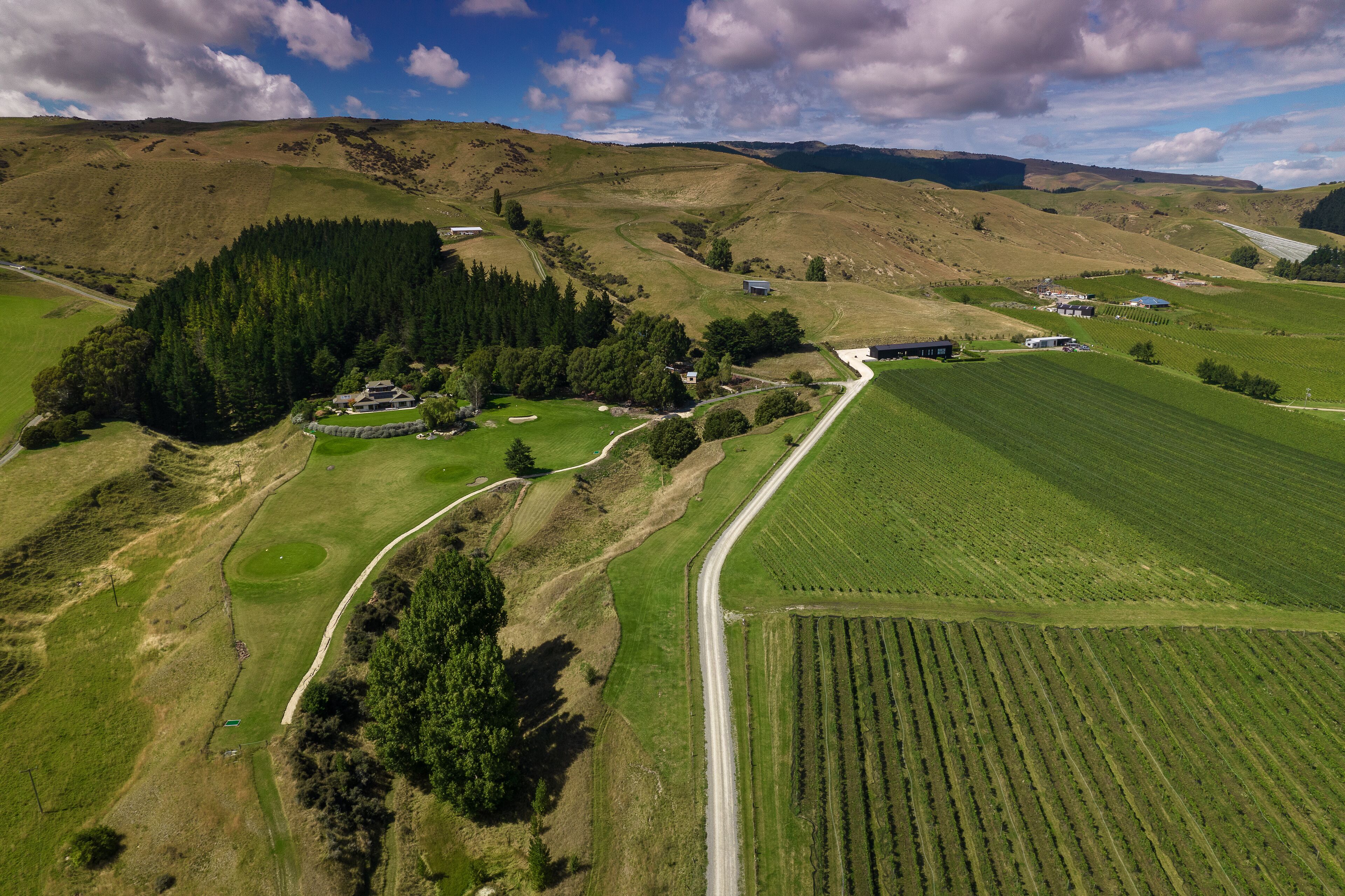 Paisaje rural con una carretera, campos y edificios dispersos.