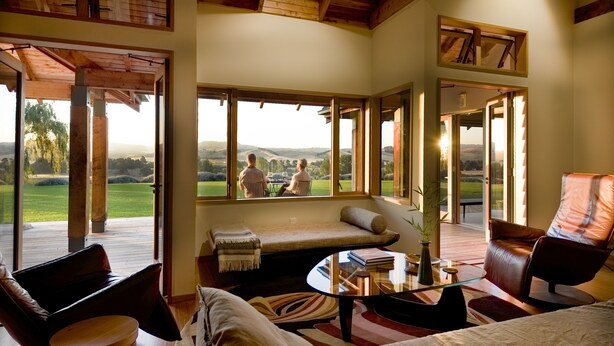 A cozy room with a large window, a sofa, a chair, and a table. - Kumiko's Guest House (Waipara)