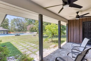A covered patio area with a pool, stone pathway, and outdoor seating.