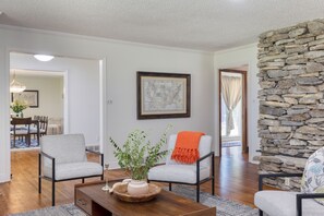 A living room with two armchairs, a coffee table, a stone wall, and a framed map on the wall.
