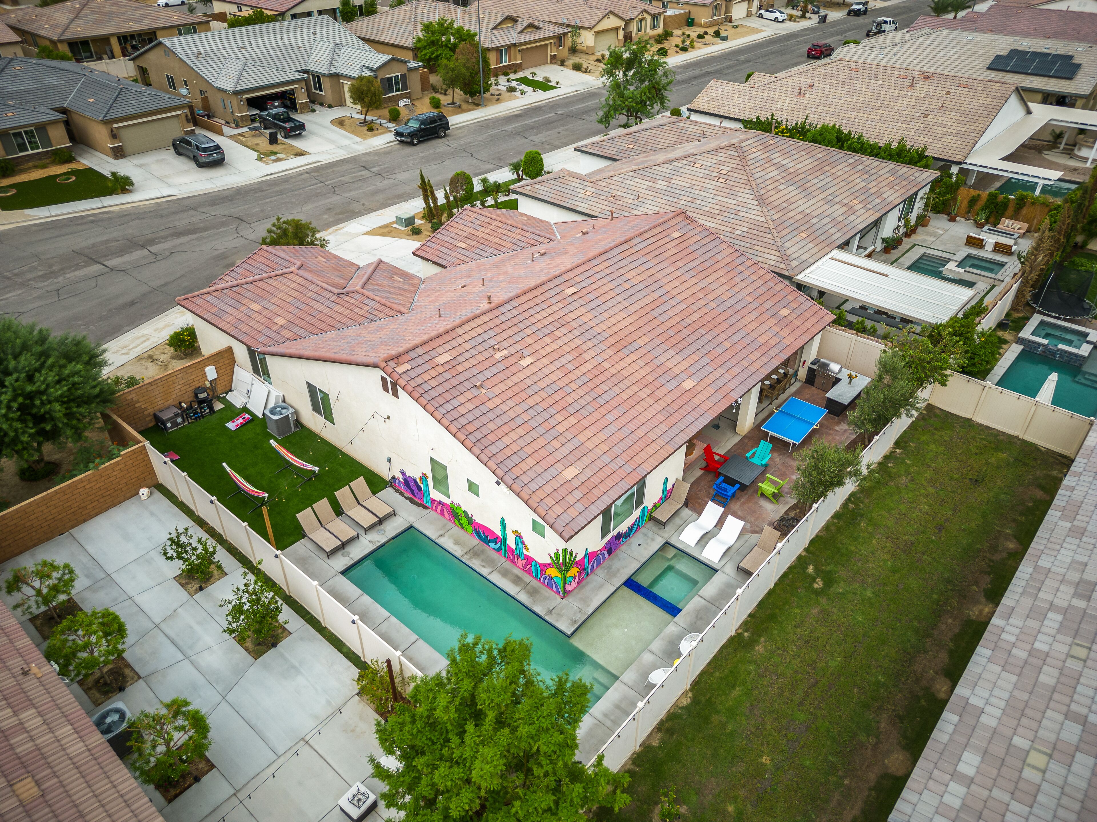A residential house with a swimming pool, a covered patio, and a fenced backyard.