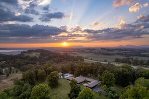 A large house with a swimming pool, surrounded by lush greenery and a scenic view of the sunset over a valley. - Cozy Studio + Hot Tub | 30 Mins to Knoxville | Amber Cabin (New Market)