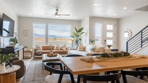 Un salón espacioso con una gran mesa de madera, asientos cómodos y vistas al paisaje des értico a través de las ventanas.