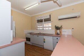 A kitchen with a gas stove, sink, and a dishwasher. - Fishing Dreams & Coastal Scenes in Onslow (Onslow)