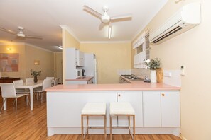 A modern kitchen with a central island, white cabinetry, and a ceiling fan. - Fishing Dreams & Coastal Scenes in Onslow (Onslow)