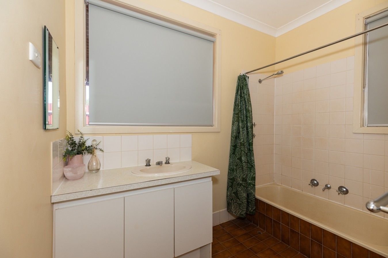 A bathroom with a white vanity, a large mirror, a shower with a glass door, and a towel hanging on a rack.