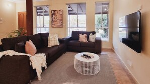 A living room with two dark sofas, a white coffee table, and a flat-screen TV mounted on the wall.