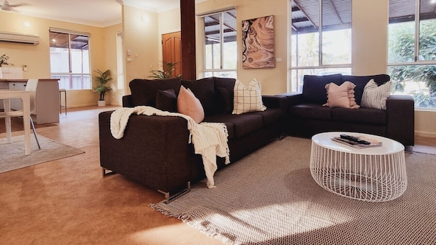 A modern living room with a sectional sofa, a coffee table, and a dining area.